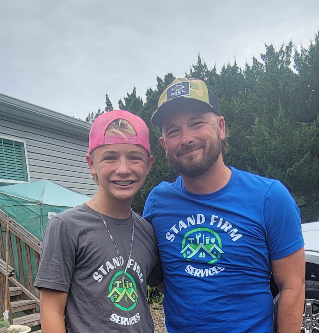 Cody and his son on a job site, both wearing branded shirts